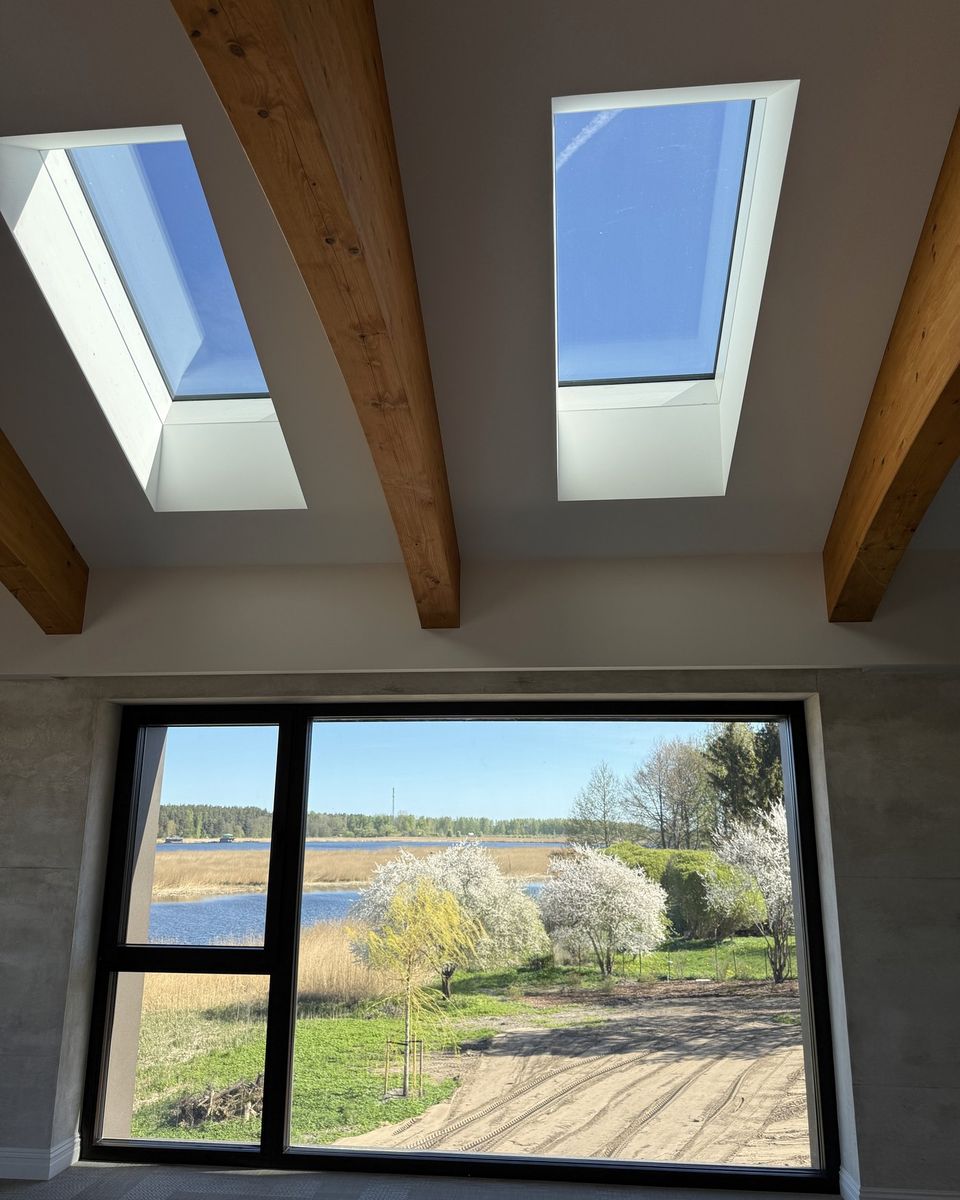 Living space with two rooflights between timber beams and a lake view